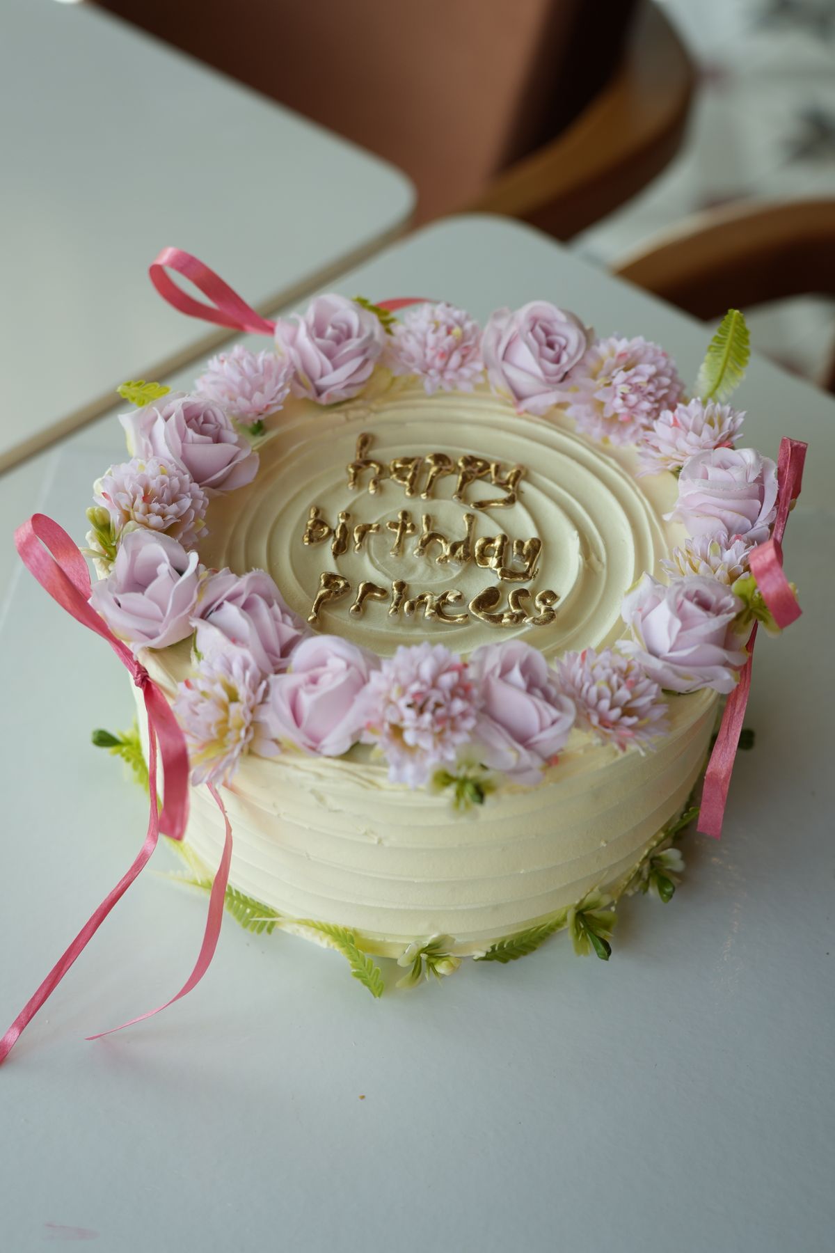 Custom bakery cake finished with fresh flowers, ribbon and hand-piped lettering
