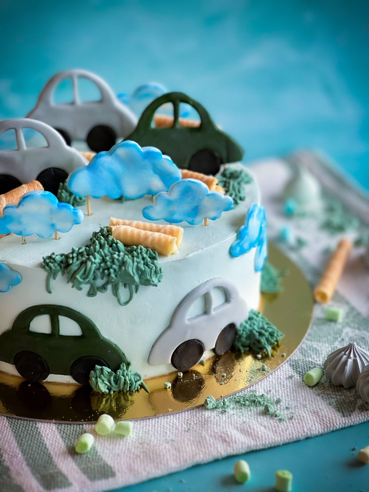 Elaborate custom bakery birthday cake with sculpted fondant cars, clouds and trees