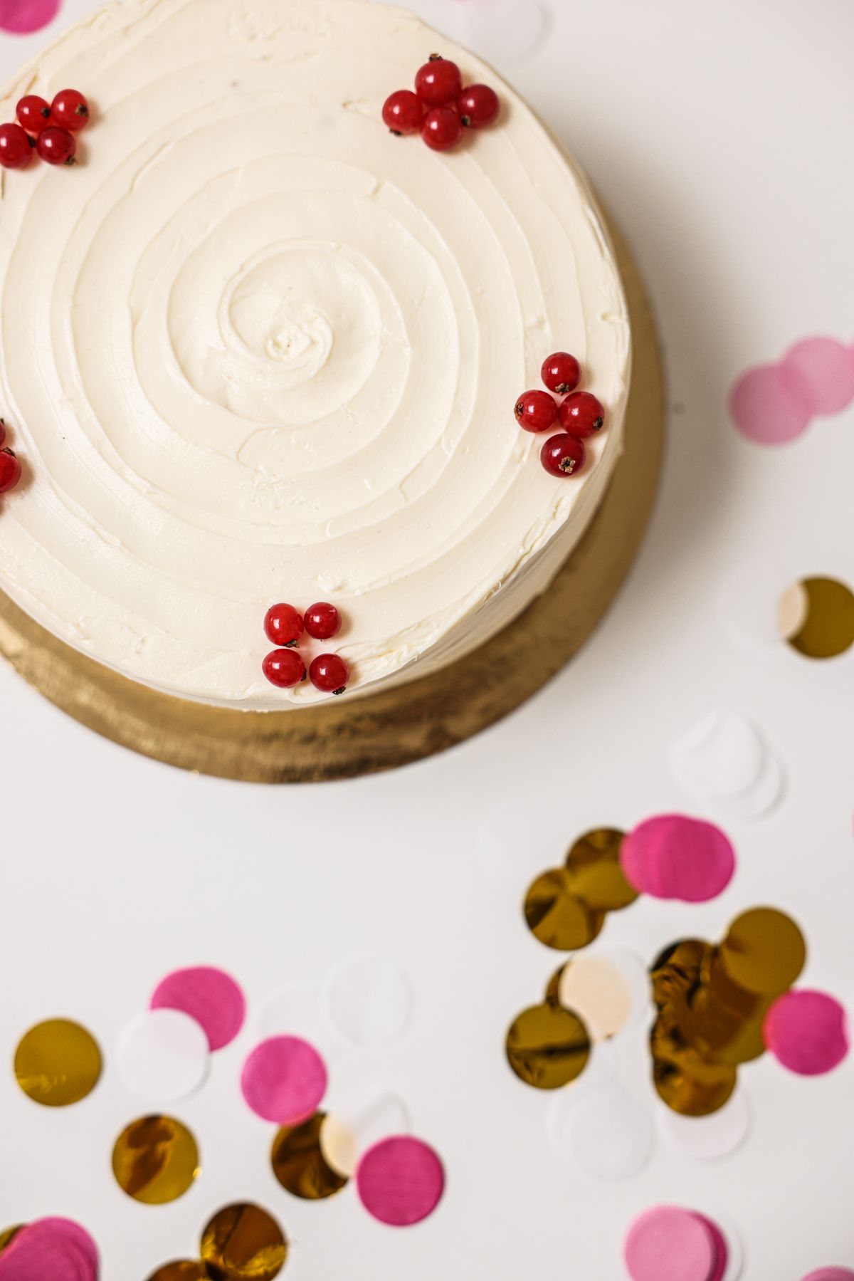 Small plain round cake with a smooth swirled buttercream top on a gold board, the look of a simple ready-made smash cake