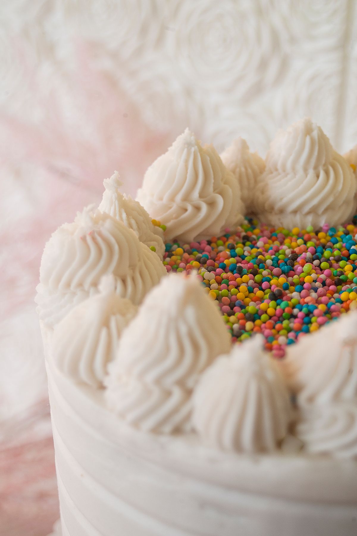Round buttercream cake with piped rosettes and rainbow sprinkles, the style of custom smash cake you can order at a grocery store bakery counter