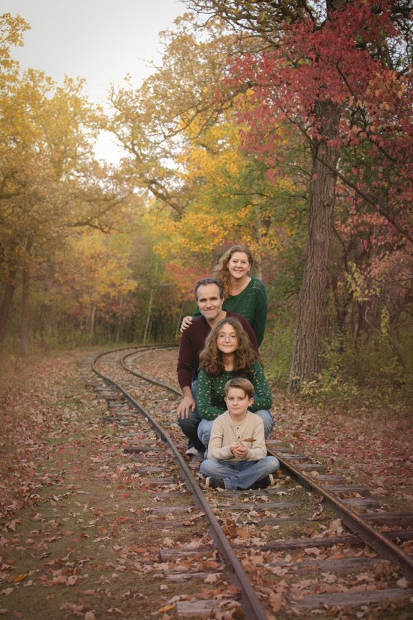 Family of four laughing together among autumn foliage